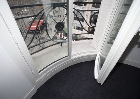 Vantail d'une fenêtre bombée ouvert sur un balcon parisien